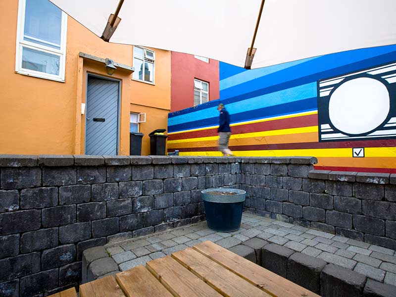 man walking by on colorful beer garden in the backyard of urban houses in reykjavik, iceland